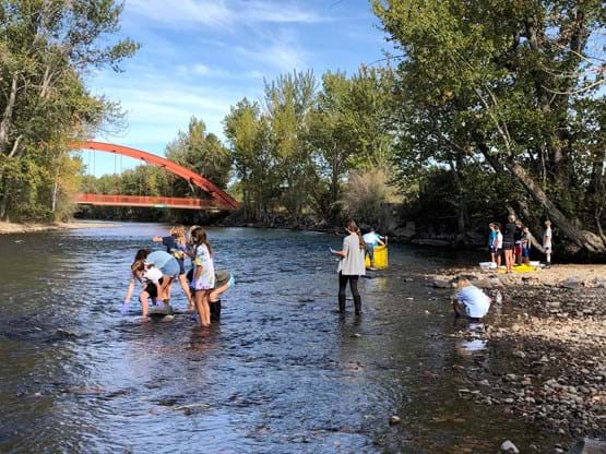 A class stands in the Boise River and takes samples of water during the day.