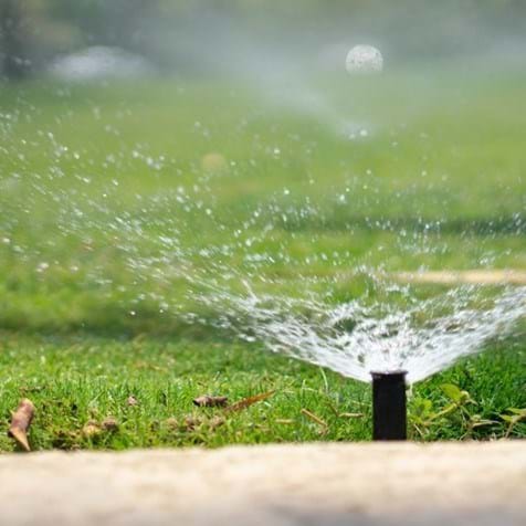 sprinkler head spraying water on green grass