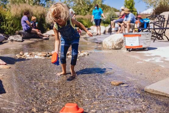 A young girl stands in water at an exhibit at WaterShed.