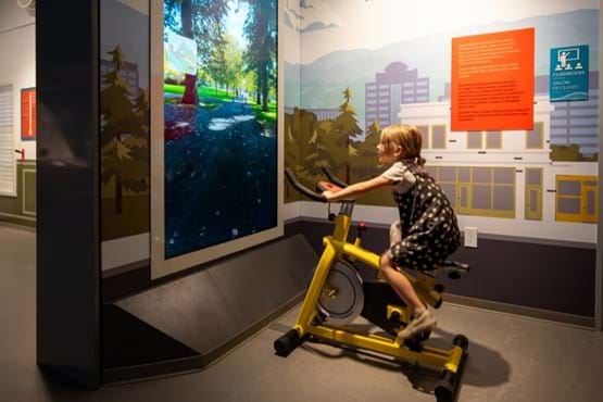 Girl uses bike exhibit at Watershed.