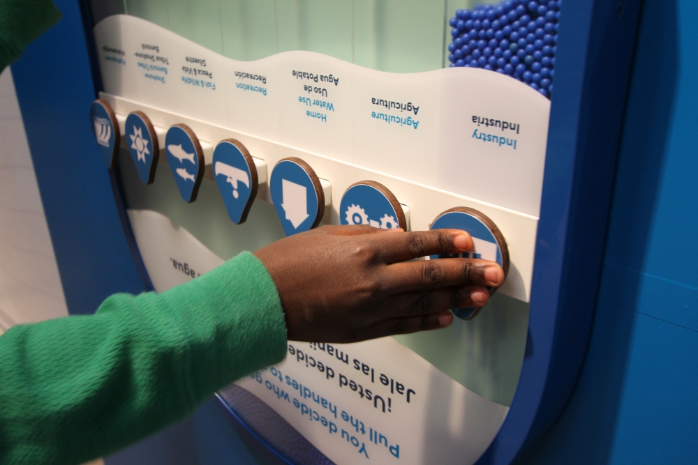An interactive exhibit where a child is moving parts that allow them to divide beads to simulate water use.