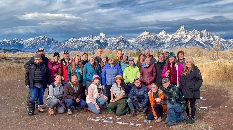 Large group of adult workshop participants posing for group photo in front of Sawtooth Mountains.